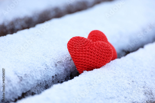 Two knitted red hearts in the snow on a park bench. Valentine s card  symbols of love  background for romantic event in winter  Christmas celebration