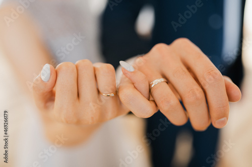 Newlyweds hold hands, hold hands together with little fingers, holding hands together in the foreground, close-up of the hands of a young couple with wedding rings on their ring fingers
