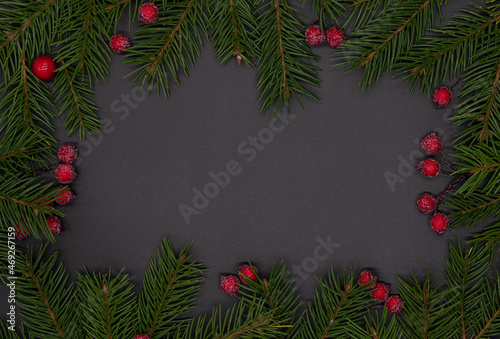 Christmas frame  banner for advertising or New Year card  pine branches  Christmas tree decorations and red berries on a black background  flat lay  top view