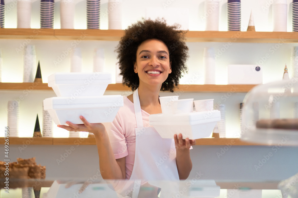 A beautiful mixed-race female worker in an ice cream parlor prepares the styrofoam boxes for delivery. A beautiful mixed-race female worker in an ice cream parlor prepares the styrofoam boxes for delivery.