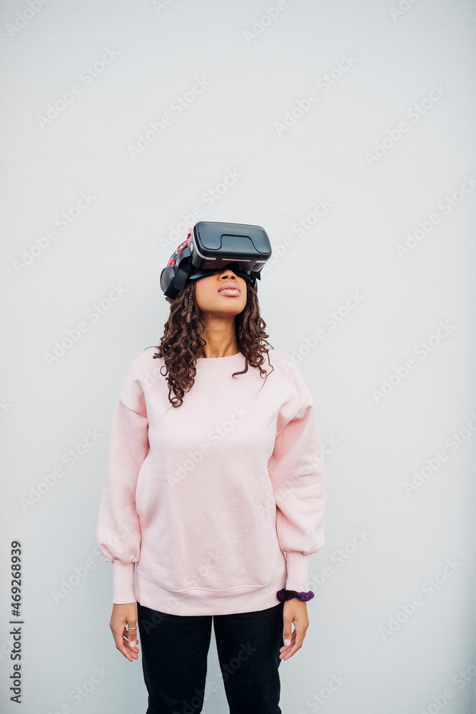 Woman using virtual reality headset in front of white wall Woman using virtual reality headset in front of white wall