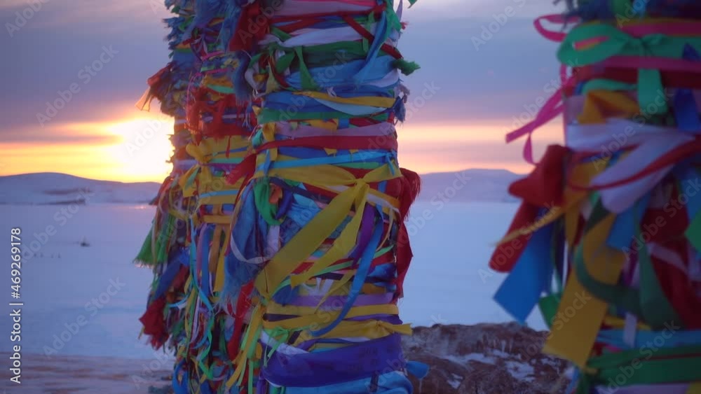 lake Baikal Serge pillars at orange sunset winter Shamanka rock, amazing Russia mystical traditional landmark. Olkhon island travel tourism. Multicolored ritual ribbons tied to flutter in wind. Gimbal