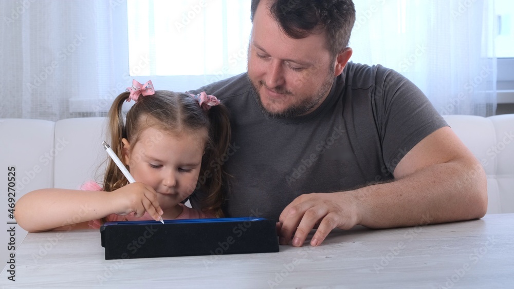 cute little girl 3 years old and her father draw draws on the tablet and at home watching a drawing lesson online. Dad rejoices at his daughters success and helps her in her studies. Online school cute little girl 3 years old and her father draw draws on the tablet and at home watching a drawing lesson online. Dad rejoices at his daughters success and helps her in her studies. Online school
