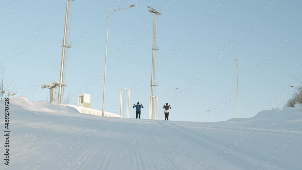 Low angle of male and female Caucasian athletes skiing downhill towards camera on white snow on sunny winter day Low angle of male and female Caucasian athletes skiing downhill towards camera on white snow on sunny winter day