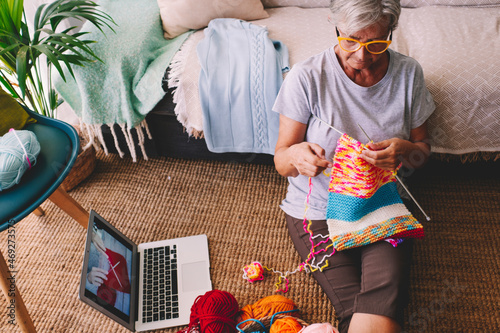 Senior woman learning knitting wool through laptop at home photo