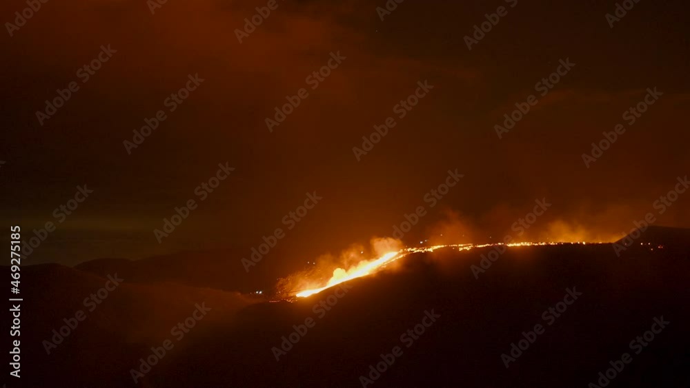 Bright glowing hot lava flowing through the landscape at night -Wide