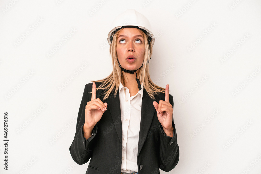 Young caucasian architect woman wearing a helmet isolated on white background pointing upside with opened mouth.