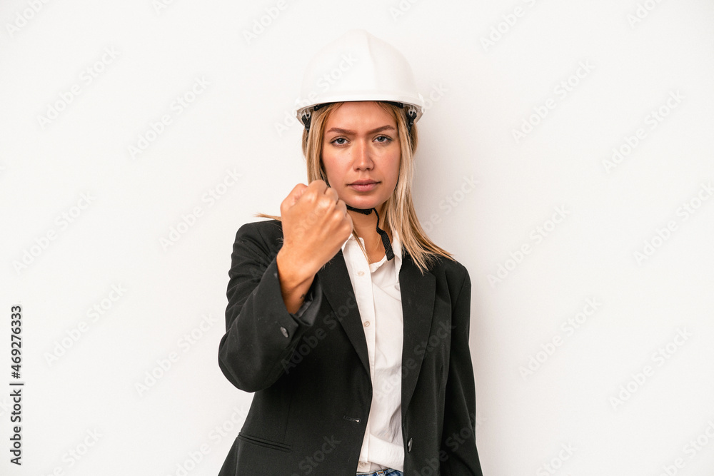 Young caucasian architect woman wearing a helmet isolated on white background showing fist to camera, aggressive facial expression. Young caucasian architect woman wearing a helmet isolated on white background showing fist to camera, aggressive facial expression.