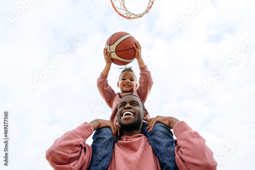 Cheerful father and son playing basketball at sports court photo