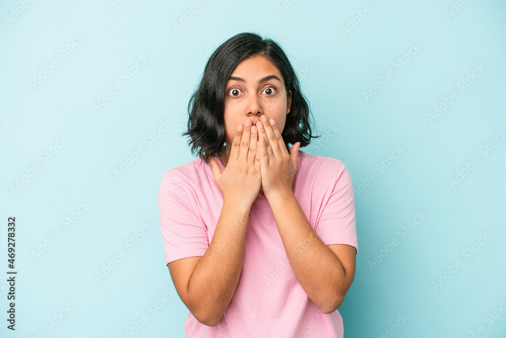 Young latin woman isolated on blue background shocked, covering mouth with hands, anxious to discover something new. Young latin woman isolated on blue background shocked, covering mouth with hands, anxious to discover something new.