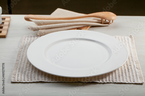 Plato redondo vacío sobre mesa con servilleta y cuchara de madera. Empty round plate on table with napkin and wooden spoon