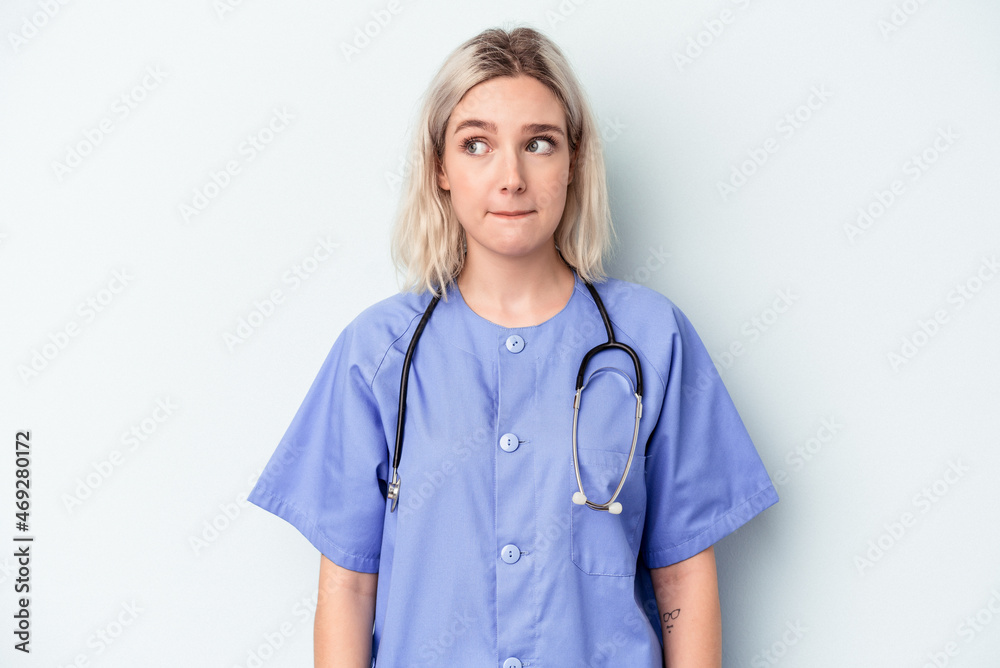 Young nurse woman isolated on blue background confused, feels doubtful and unsure. Young nurse woman isolated on blue background confused, feels doubtful and unsure.