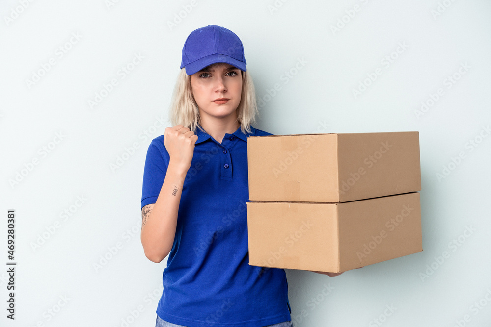Young delivery caucasian woman isolated on blue background showing fist to camera, aggressive facial expression. Young delivery caucasian woman isolated on blue background showing fist to camera, aggressive facial expression.