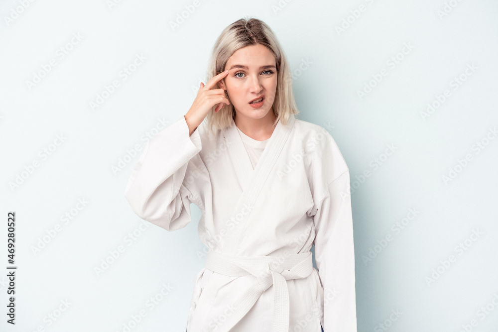Young caucasian woman doing karate isolated on blue background showing a disappointment gesture with forefinger. Young caucasian woman doing karate isolated on blue background showing a disappointment gesture with forefinger.