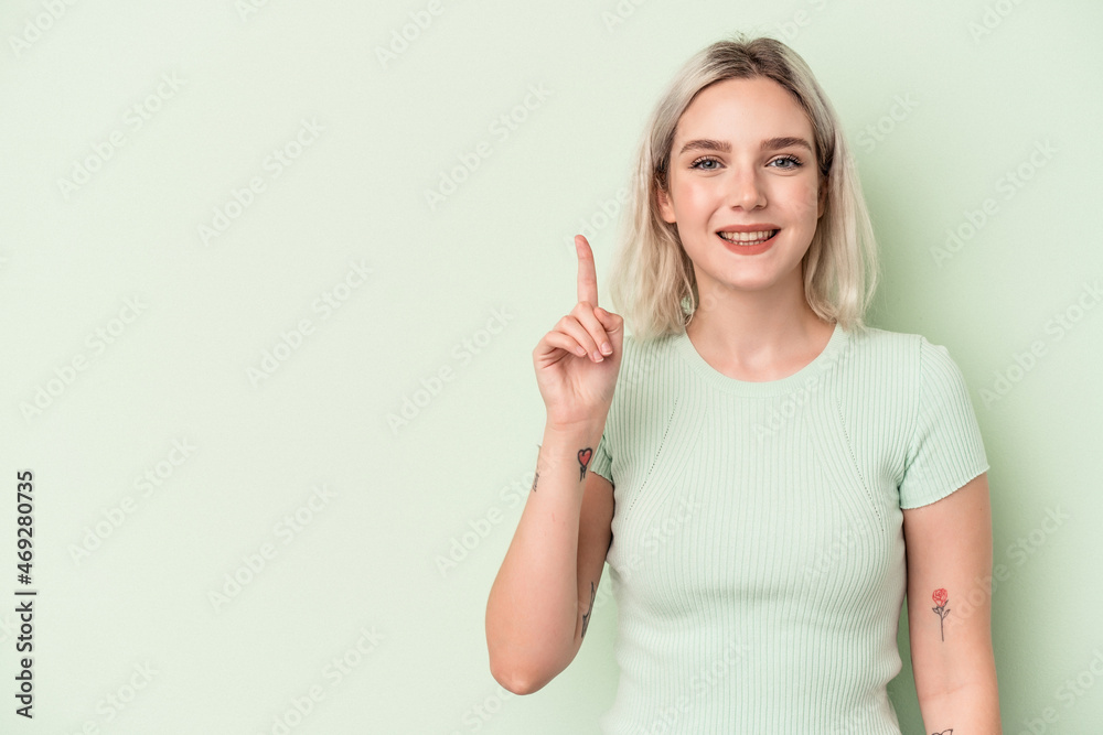 Young caucasian woman isolated on green background showing number one with finger. Young caucasian woman isolated on green background showing number one with finger.