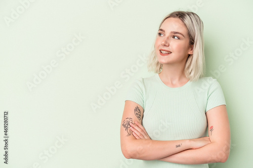 Young caucasian woman isolated on green background smiling confident with crossed arms.