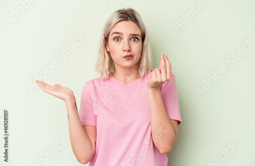 Young caucasian woman isolated on green background showing that she has no money.