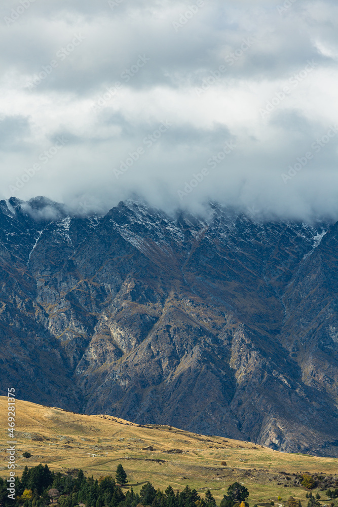 Fototapeta premium ニュージーランド クイーンズタウンのワカティプ湖の湖畔から見える雲のかかったリマーカブルズ山脈