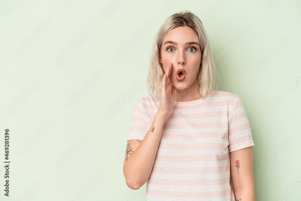 Young caucasian woman isolated on green background is saying a secret hot braking news and looking aside