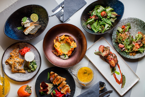 Set of various restaurant meals on gray background. Collage of different main courses, meat and fish dishes with garnish, salads and desserts, business lunch concept, top view