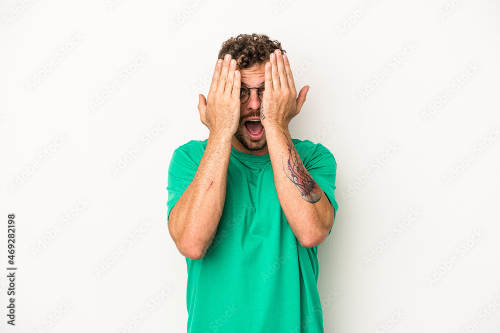 Young caucasian man isolated on white background having fun covering half of face with palm. Young caucasian man isolated on white background having fun covering half of face with palm.