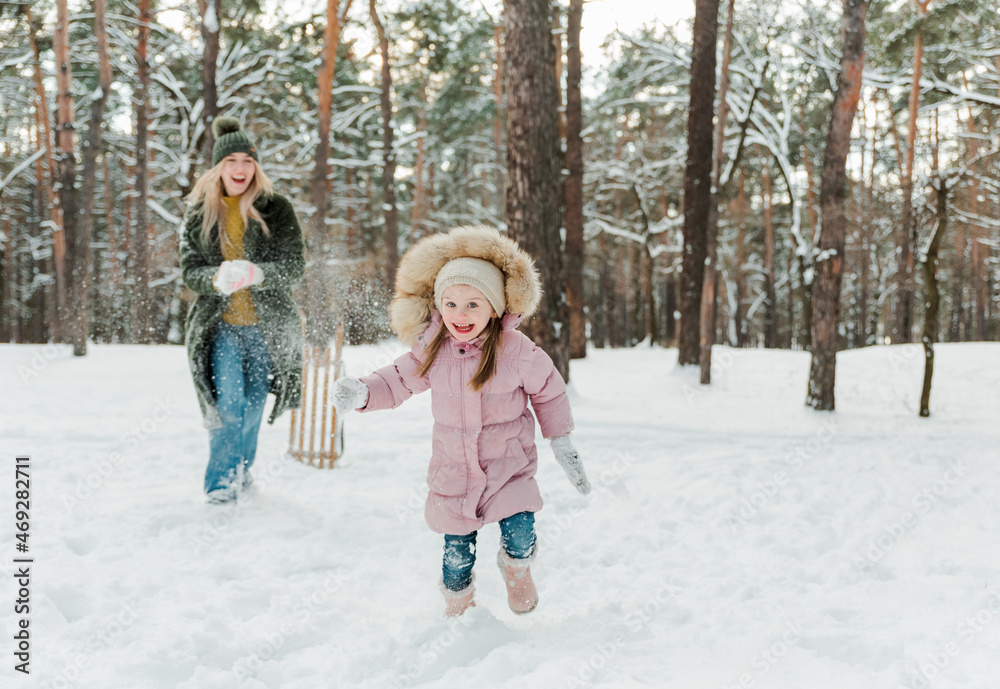 Obraz premium Happy and smilling young mother and her little daughter having fun outside, in winter park