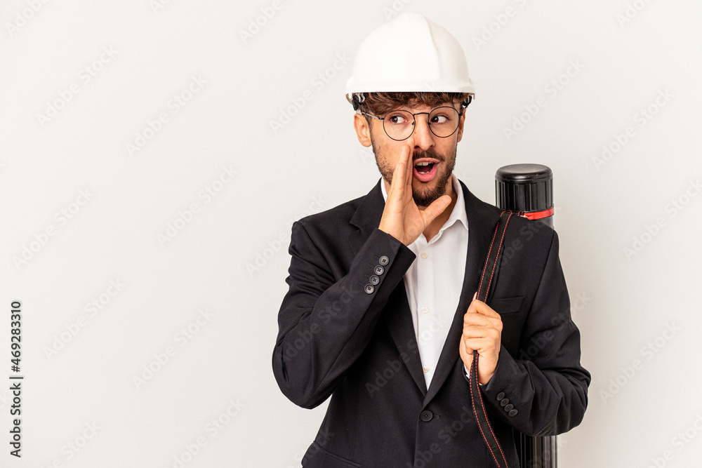 Young mixed race architect man wearing a helmet isolated on grey background is saying a secret hot braking news and looking aside