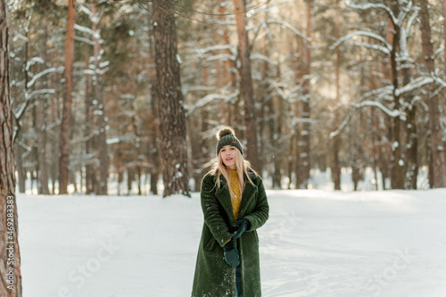 Pretty young blond woman, dressed warmly, with a scarf and mittens. Beautiful girl having fun in the snow