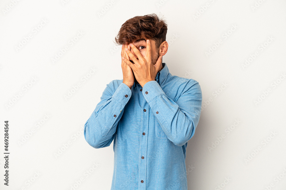 Young mixed race man isolated on grey background blink through fingers frightened and nervous. Young mixed race man isolated on grey background blink through fingers frightened and nervous.