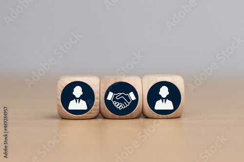 wooden cube with businessman icon and handshake icon. Teamwork concept.