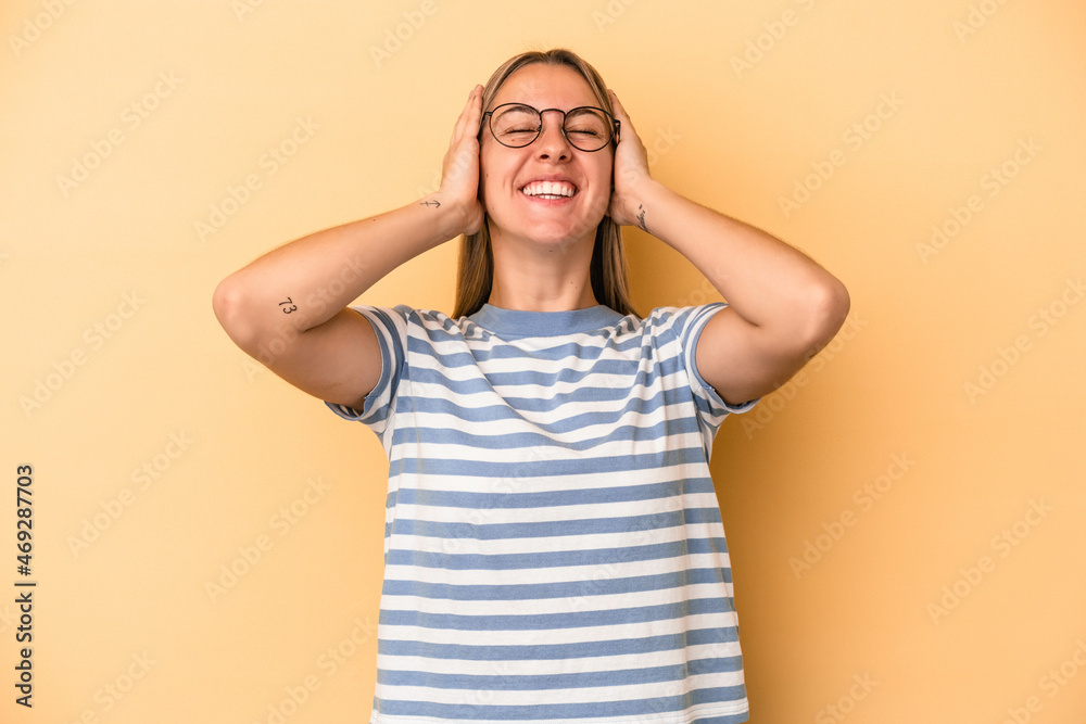 Young caucasian woman isolated on yellow background laughs joyfully keeping hands on head. Happiness concept. Young caucasian woman isolated on yellow background laughs joyfully keeping hands on head. Happiness concept.
