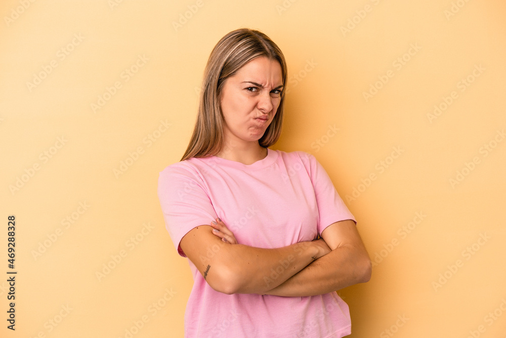 Fototapeta premium Young caucasian woman isolated on yellow background frowning face in displeasure, keeps arms folded.