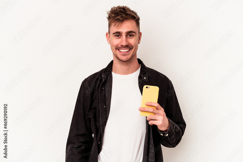 Young caucasian man holding a mobile phone isolated on white background happy, smiling and cheerful. Young caucasian man holding a mobile phone isolated on white background happy, smiling and cheerful.