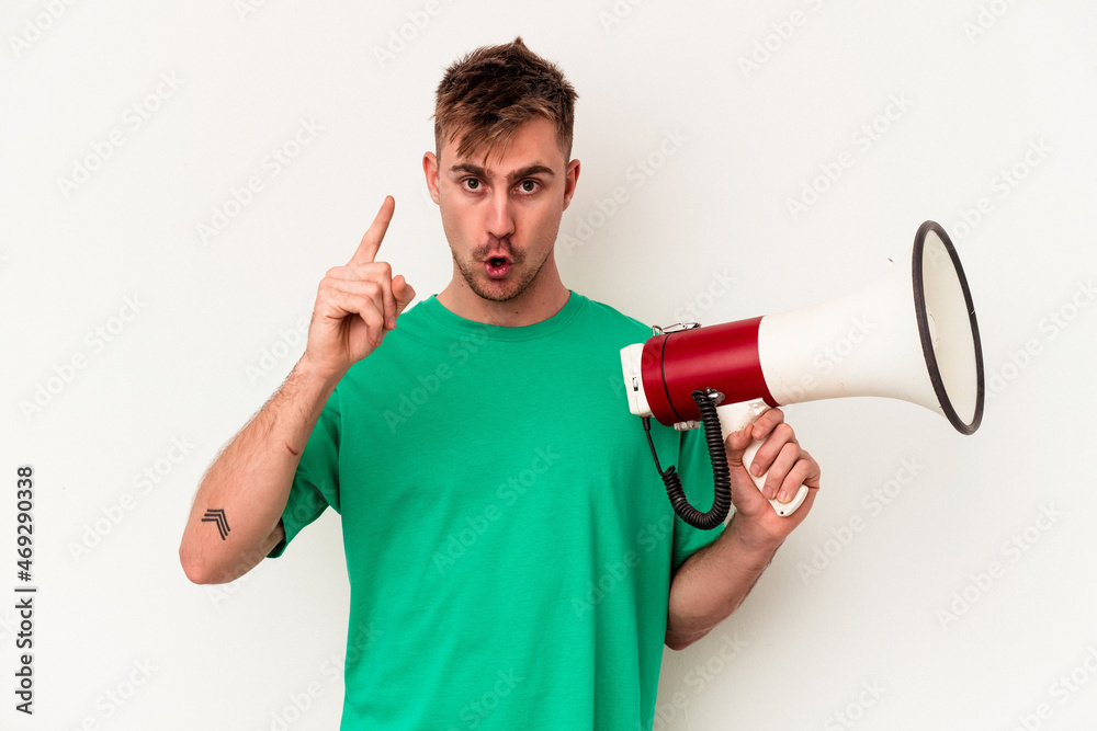 Young caucasian man holding megaphone isolated on white background having an idea, inspiration concept. Young caucasian man holding megaphone isolated on white background having an idea, inspiration concept.
