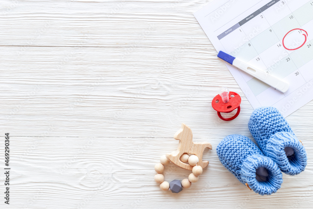 Blue baby boy booties with pregnancy test on calendar, top view Blue baby boy booties with pregnancy test on calendar, top view