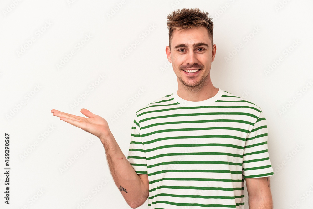 Young caucasian man isolated on white background showing a copy space on a palm and holding another hand on waist. Young caucasian man isolated on white background showing a copy space on a palm and holding another hand on waist.