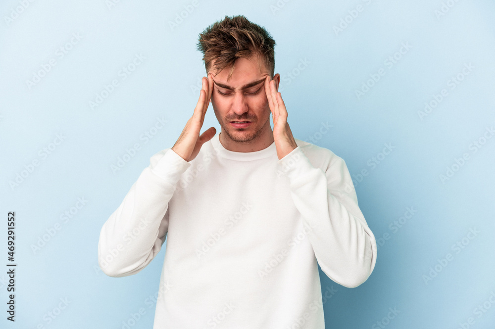 Young caucasian man isolated on blue background touching temples and having headache. Young caucasian man isolated on blue background touching temples and having headache.