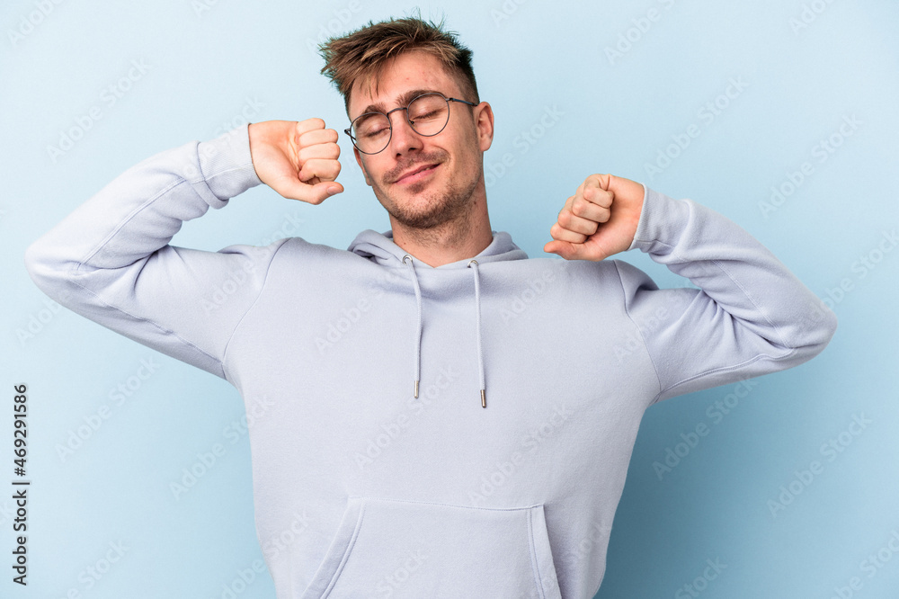 Young caucasian man isolated on blue background stretching arms, relaxed position. Young caucasian man isolated on blue background stretching arms, relaxed position.