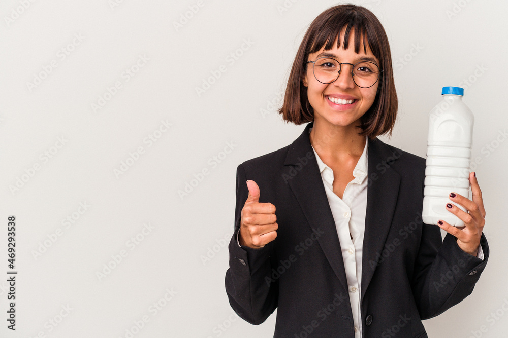 Young mixed race business woman holding a milk bottle isolated on white background smiling and raising thumb up Young mixed race business woman holding a milk bottle isolated on white background smiling and raising thumb up