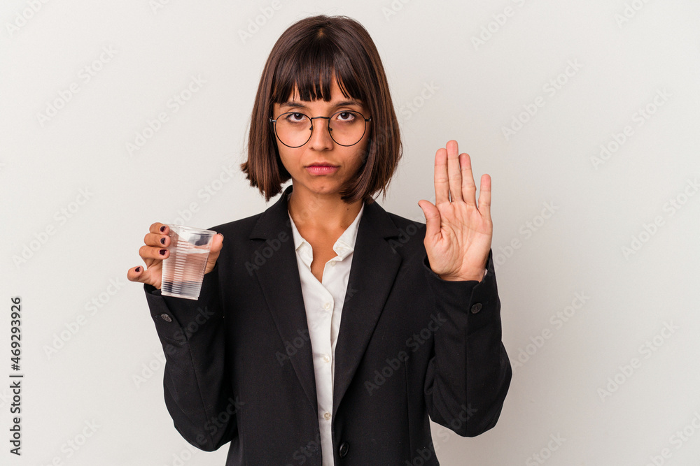 Young mixed race business woman holding a glass of water isolated on white background standing with outstretched hand showing stop sign, preventing you. Young mixed race business woman holding a glass of water isolated on white background standing with outstretched hand showing stop sign, preventing you.