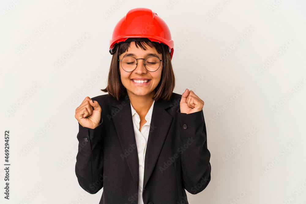 Young architect woman with red helmet isolated on white background raising fist, feeling happy and successful. Victory concept. Young architect woman with red helmet isolated on white background raising fist, feeling happy and successful. Victory concept.