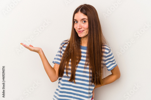 Young caucasian woman isolated on white background showing a copy space on a palm and holding another hand on waist.