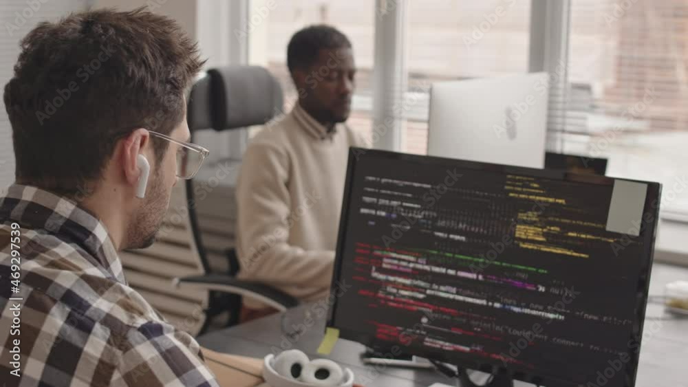 Stab shot of team of software developers or engineers working with program codes on computer screens in modern office