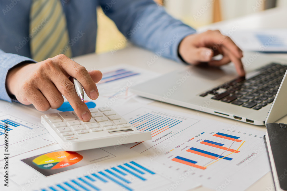 a businessman pressing his finger on a calculator to calculate expenses Finance is calculating tax information. and analyze financial stock charts that are in good shape with growth and progress. a businessman pressing his finger on a calculator to calculate expenses Finance is calculating tax information. and analyze financial stock charts that are in good shape with growth and progress.