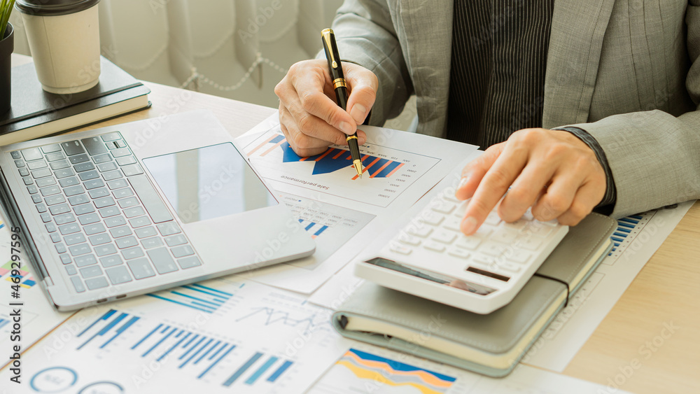 a businessman pressing his finger on a calculator to calculate expenses Finance is calculating tax information. and analyze financial stock charts that are in good shape with growth and progress. a businessman pressing his finger on a calculator to calculate expenses Finance is calculating tax information. and analyze financial stock charts that are in good shape with growth and progress.