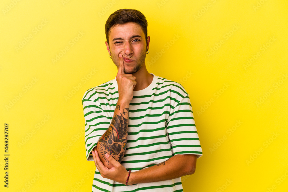 Young caucasian man with tattoos isolated on yellow background unhappy looking in camera with sarcastic expression. Young caucasian man with tattoos isolated on yellow background unhappy looking in camera with sarcastic expression.