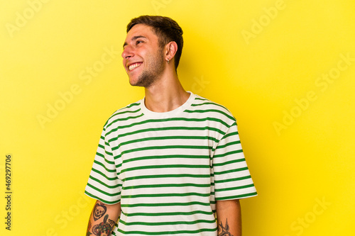 Young caucasian man with tattoos isolated on yellow background dancing and having fun.