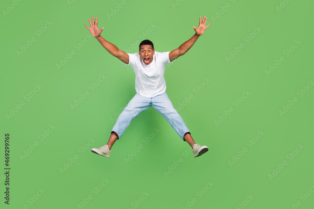 Full size photo of young african man amazed shock surprised jump up isolated over green color background