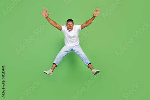 Full size photo of young african man amazed shock surprised jump up isolated over green color background