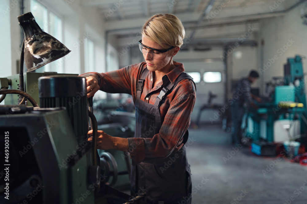 Portrait of mid adult industrial woman working indoors in metal workshop.